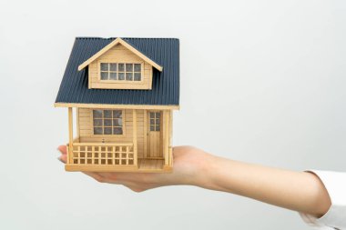 Beyaz arka planda izole edilmiş bir ev modeli tutan beyaz bir kadın.