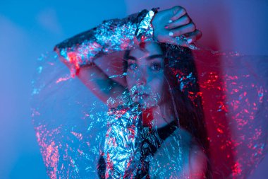 Renkli parlak neon ışıklarıyla stüdyoda poz veren yüksek model kadın. Parlak makyajlı güzel bir kızın portresi. Renkli canlı arkaplanda sanat tasarımı canlı stili