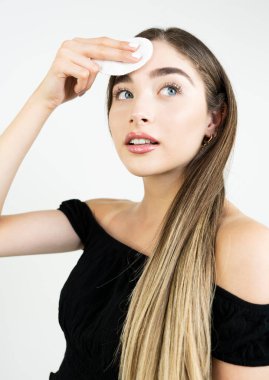 Güzel sarışın kadın pamukla makyajını temizliyor. 