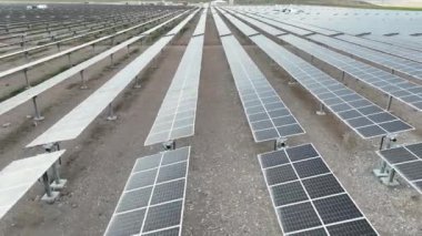 Elektrik santralindeki güneş panelleri. Fotovoltaik panellerle güneş enerjisini tarım arazilerindeki yeşil enerji için elektriğe dönüştüren bir güneş çiftliğinin üzerinde uçmak