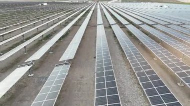 Elektrik santralindeki güneş panelleri. Fotovoltaik panellerle güneş enerjisini tarım arazilerindeki yeşil enerji için elektriğe dönüştüren bir güneş çiftliğinin üzerinde uçmak