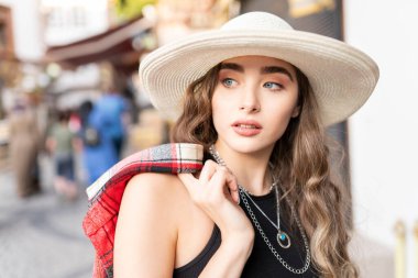 Hasır şapkayla bavulla poz veren güzel bir kız.