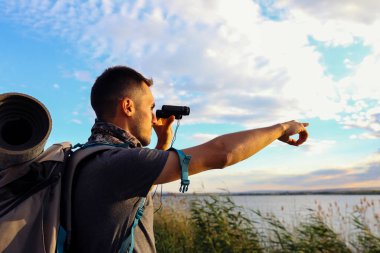 Gökyüzünün arka planında dürbünü olan ve parmağını işaret eden bir adam.