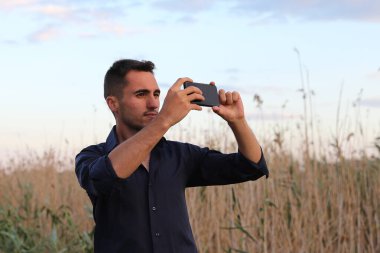 Kameralı genç adam gün batımında sahada fotoğraf çekiyor.. 