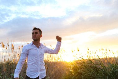 Gün batımında sahada yumruğu olan genç bir adam.