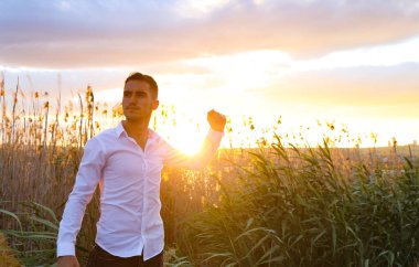 Gün batımında sahada yumruğu olan genç bir adam.
