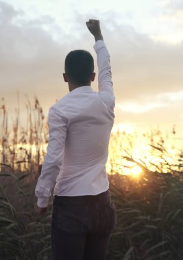 Gün batımında sahada yumruğu olan genç bir adam.