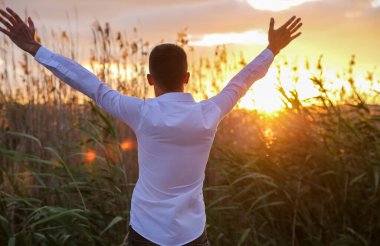 Genç adam kollarını doğaya doğru açmış.