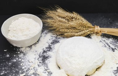 Hamur, buğday ve un başakları masada.