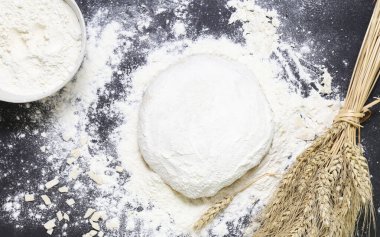 Hamur, buğday ve un başakları masada.