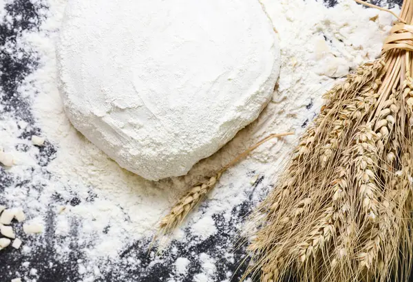 Hamur, buğday ve un başakları masada.