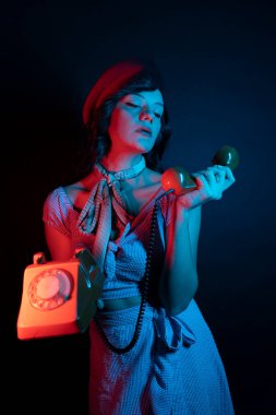 Turuncu Retro Telefondan Konuşan Genç Kadın. Renkli parlak neon ışıklarıyla stüdyoda poz veren yüksek model kadın..