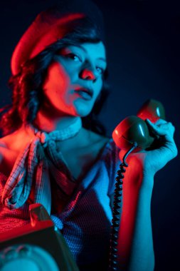 Turuncu Retro Telefondan Konuşan Genç Kadın. Renkli parlak neon ışıklarıyla stüdyoda poz veren yüksek model kadın..