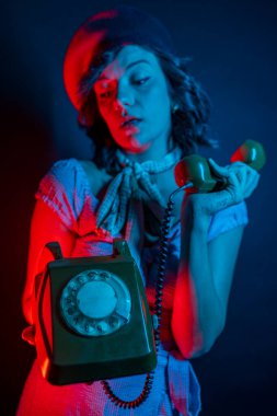 Turuncu Retro Telefondan Konuşan Genç Kadın. Renkli parlak neon ışıklarıyla stüdyoda poz veren yüksek model kadın..
