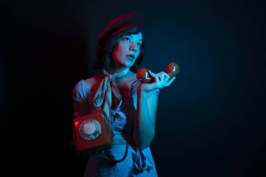 Turuncu Retro Telefondan Konuşan Genç Kadın. Renkli parlak neon ışıklarıyla stüdyoda poz veren yüksek model kadın..