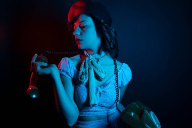 Turuncu Retro Telefondan Konuşan Genç Kadın. Renkli parlak neon ışıklarıyla stüdyoda poz veren yüksek model kadın..