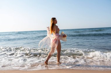 Gün batımında kumsalda yürüyen mutlu bir kadın. Güzel bir kadın. Mutlu bir kadın. Hayat tarzı kadınlar plaj konseptiyle seyahat eder..