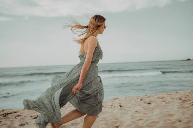 Gün batımında kumsalda yürüyen mutlu bir kadın. Güzel bir kadın. Mutlu bir kadın..