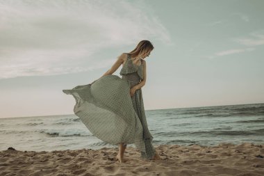 Gün batımında kumsalda yürüyen mutlu bir kadın. Güzel bir kadın. Mutlu bir kadın..