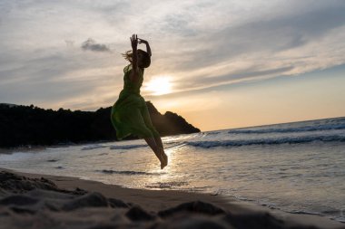 Gün batımında kumsalda yürüyen mutlu bir kadın. Güzel bir kadın. Mutlu bir kadın..