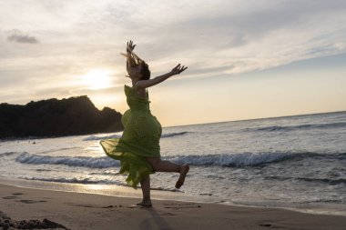 Gün batımında kumsalda yürüyen mutlu bir kadın. Güzel bir kadın. Mutlu bir kadın..