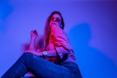 Renkli parlak neon ışıklarıyla stüdyoda poz veren yüksek model kadın. Parlak makyajlı güzel bir kadının portresi. Sanat tasarımı canlı biçimi