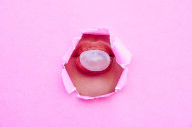 Pembe yırtık bir kağıttan ağzına sakız üfleyen bir kadın. Reklam ve yaratıcı konsept. reklam için kopyalama alanı