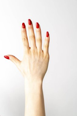 Üzerinde kırmızı oje olan bir kadın eli. Kadın eli beş numaralı beyaz arka planı gösteriyor.