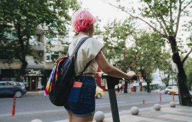 Şehirde elektrikli scooter kullanan genç bir kadın.