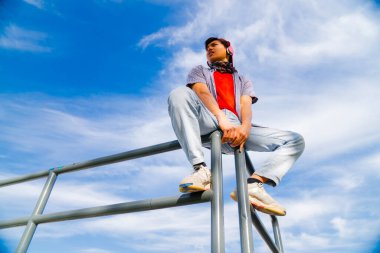 Asyalı genç adam kulaklıkla müzik dinliyor.