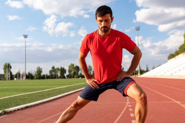 Sporcu egzersizden önce ısınarak ısınıyor. Adam egzersizden önce esneme egzersizleri yapıyor.