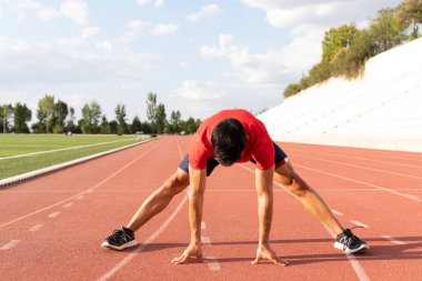 Sporcu egzersizden önce ısınarak ısınıyor. Adam egzersizden önce esneme egzersizleri yapıyor.