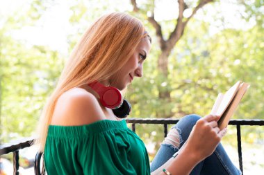 Balkonda kitap okuyan mutlu kadın.