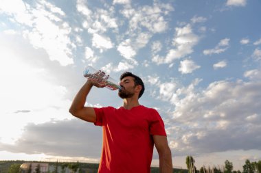 Adam spordan sonra açık havada su içiyor.