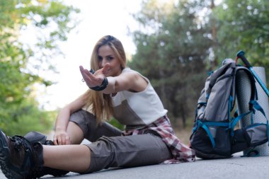 Gezgin bir kadın sırt çantasıyla birlikte yolda oturuyor. seyahat ve seyahat kavramı