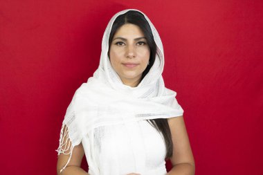 Stüdyoda beyaz eşarplı bir kadının portresi. Ortadoğulu genç bayan kırmızı arka plan