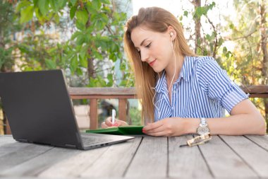 Kadın dışarıda bir restoranda bilgisayar öğreniyor ve kullanıyor.