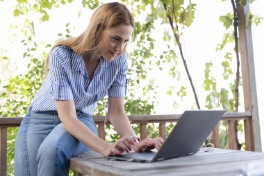 Kadın dışarıda bir restoranda bilgisayar öğreniyor ve kullanıyor.