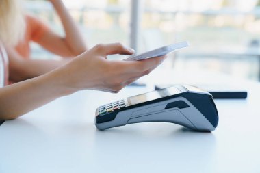 Lokantada NFC teknolojisi kullanan bir kadın faturayı akıllı telefondan ödüyor..
