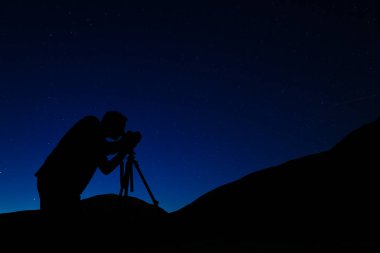 Gece gökyüzünün fotoğraflarını çeken bir fotoğrafçı. İnsan silueti, yıldızlı gökyüzünün arka planına karşı. Yıldızlar