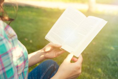 Parkta kitap okuyan güzel genç bir kadın.       