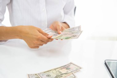 Bir kadın birçok Amerikan banknotunu sayar.
