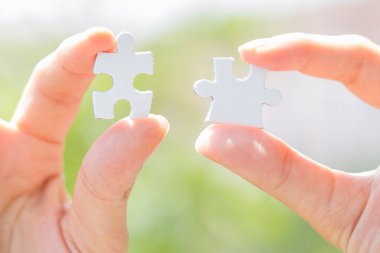 Yapboz parçalarını birleştirmeye çalışan ellerin yakın görüntüsü