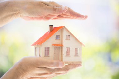 Küçük model evi tutan eller. Ev koruma kavramı