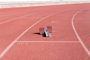 Atletizm stadyumunun kül izindeki boş başlangıç blokları. Kırmızı tamrac üzerine boyanmış çalışan parçaları