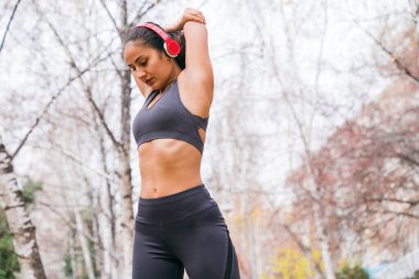 Genç kadın parkta koşmadan önce geriniyor.