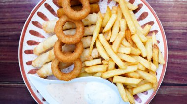 Bir tabak beyaz soslu yemek ve bir tabak patates kızartması.