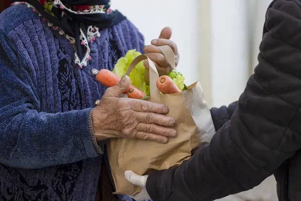 Süpermarketten yaşlı bir kadın için market teslimatı. Ev girişinde yaşlı bayan müşteriyle sağlık, alışveriş ve kadın. Perakende kuryeden sağlıklı yiyecek ve bakkaliye poşeti.