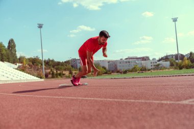 Erkek sporcu başlangıç pozisyonunda kararlı ve odaklanmış görünüyor