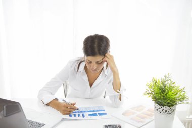 Önünde bir yığın kağıtla bir iş kadını masada oturuyor.